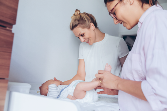 Frauen mit Baby auf Wickeltisch beim Windelwechseln