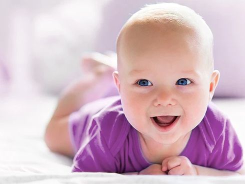 Lachendes Baby mit lila Oberteil und blauen Augen