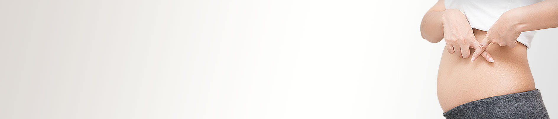 Frau mit leichtem Schwangerschaftsbauch zeigt Kreuz mit Zeigefinger