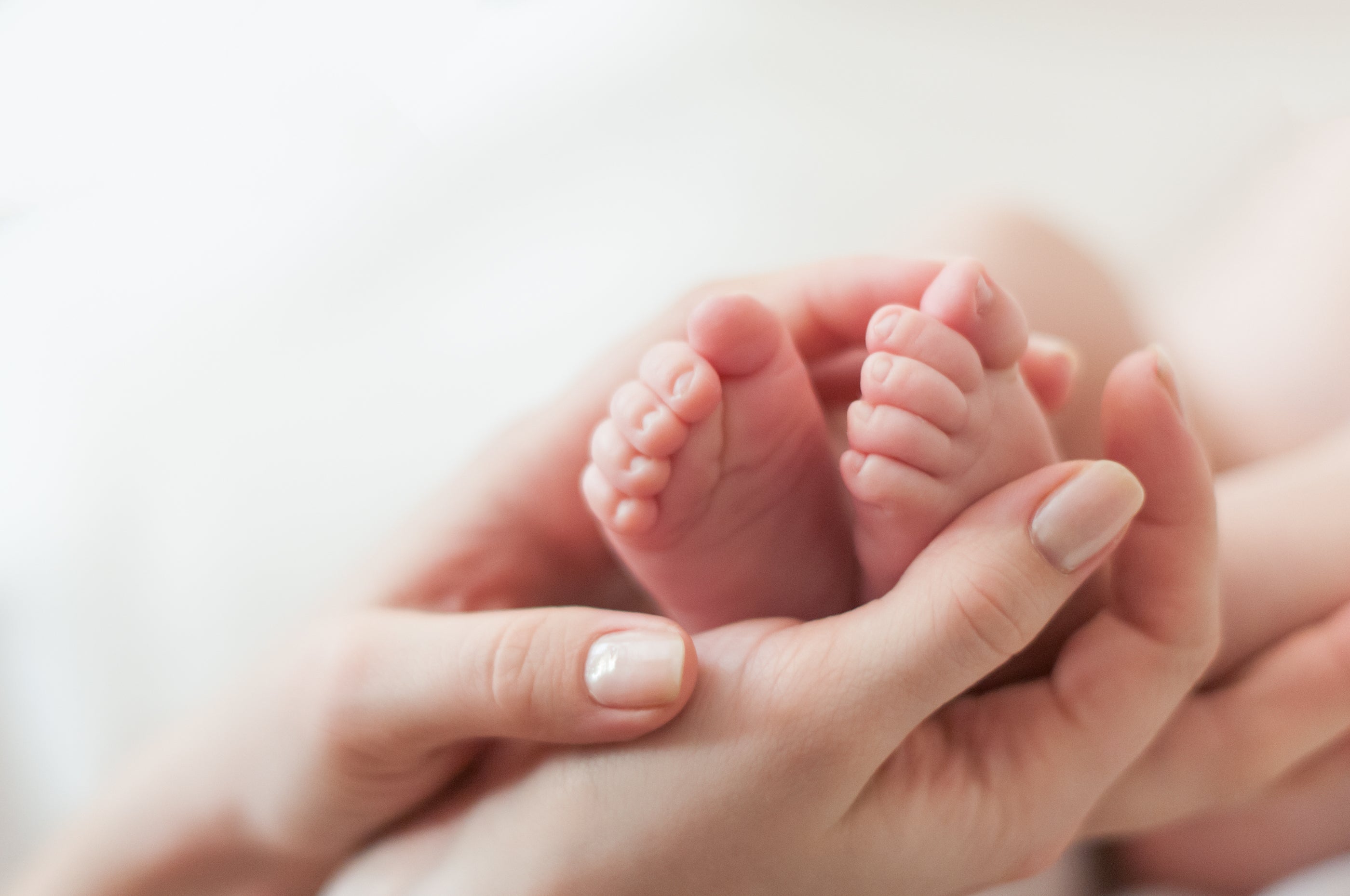 Frauenhände halten Babyfüße