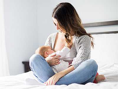 Baby wird von dunkelhaariger Mutter gestillt