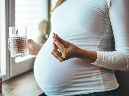 Frau mit Babybauch die Tablette einnimmt