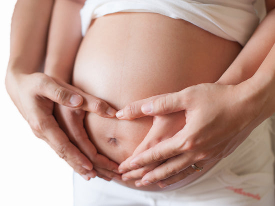 Schwangerschaftsbauch, der umarmt wird von Paar